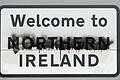 Auf einem beschmierten Straßenschild an der Grenze zwischen Donegal und Derry steht 'Welcome to Northern Ireland' (Willkommen in Nordirland).