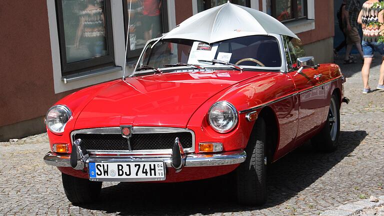 Bevor es dem Oldtimer zu heiß wird, erhält der Liebling auf vier Rädern einen Sonnenschirm. Gesehen während der 'Geo Classics' am 21. August in Gerolzhofen.