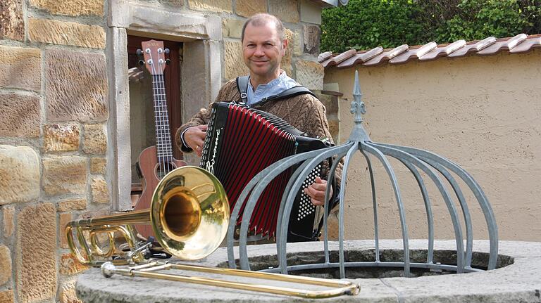 Ralph Theobald spielt wie seine Band-Kollegen von 'Häisd'n'däisd vomm Mee' mehrere Instrumente, wie das Akkordeon, das er in Händen hält, die Posaune (vorne) und die Ukulele (hinten im Fenster). Ralph Theobald spielt wie seine Band-Kollegen von 'Häisd'n'däisd vomm Mee' mehrere Instrumente, wie das Akkordeon, das er in Händen hält, die Posaune (vorne) und die Ukulele (hinten im Fenster).