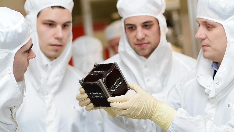 Im Testlabor an der Uni Würzburg betrachten Doktorand Stephan Busch (rechts) und sein Team den Kleinsatelliten 'Uwe 3' (Archivbild). Eine russische Rakete hat ihn vor sieben Jahren ins All befördert. Die Universität hat sich in der Raumfahrtforschung mit ihren Satelliten-Entwicklungen einen Namen gemacht.