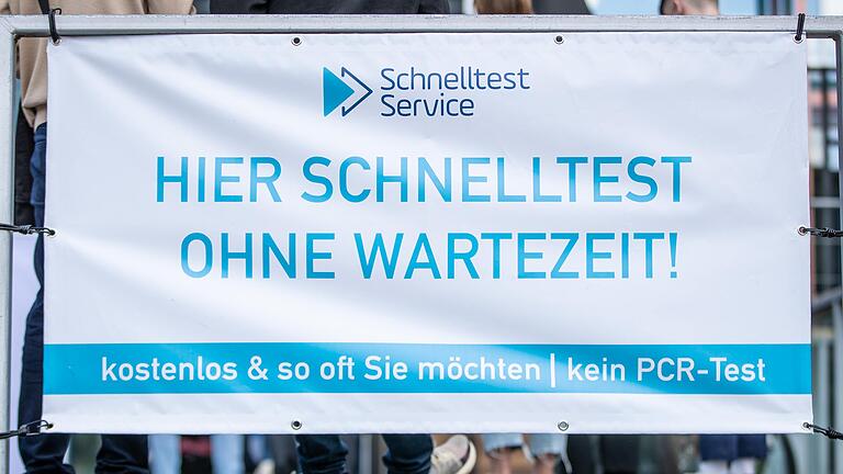 Vor einem Testzentrum an einem Transparent mit der Aufschrift 'Hier Schnelltest - Ohne Wartezeit'. Restaurants, Hotels und der Einzelhandel dürfen wieder aufmachen - Besucher müssen geimpft oder genesen sein oder einen negativen Test vorlegen.&nbsp;