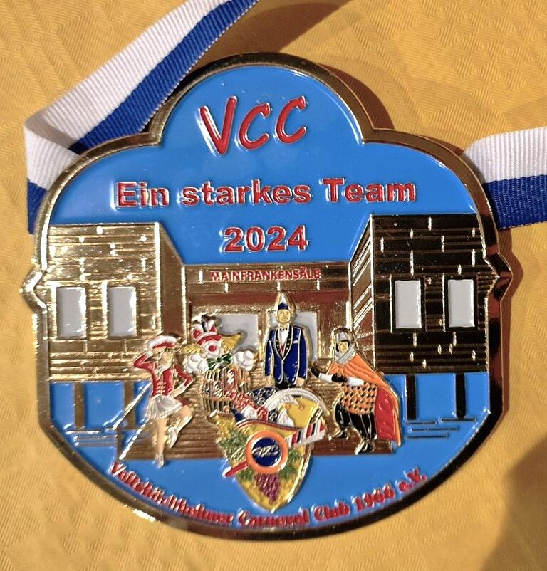 Der neue Sessionorden des VCC trägt das Motto 'Ein starkes Team 2024'. Vor dem Großtempel der Fastnacht unserer Veitshöchheimer Mainfrankensäle stehen Garde, Büttenredner, Elferräte und Schlappsäue zusammen.