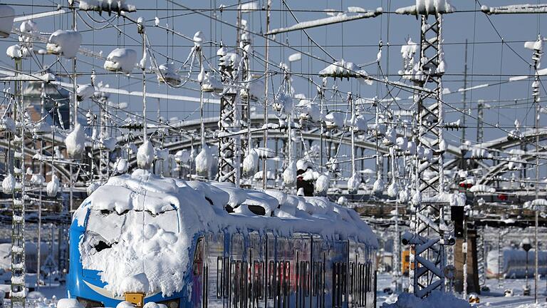 Winterwetter am Münchener Hauptbahnhof.jpeg       -  Ein mit Schnee bedeckter Regionalzug steht im Hauptbahnhof in München.