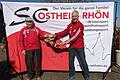 Der 84-jährige Sportsmann Johann Urban (links) übergibt seine historischen Rennschuhe an Eberhard Helm (rechts), den Vorsitzenden des SC Ostheim. Hier dienen sie in Zukunft als Vorbild für sportliche Betätigung und Gesunderhaltung.