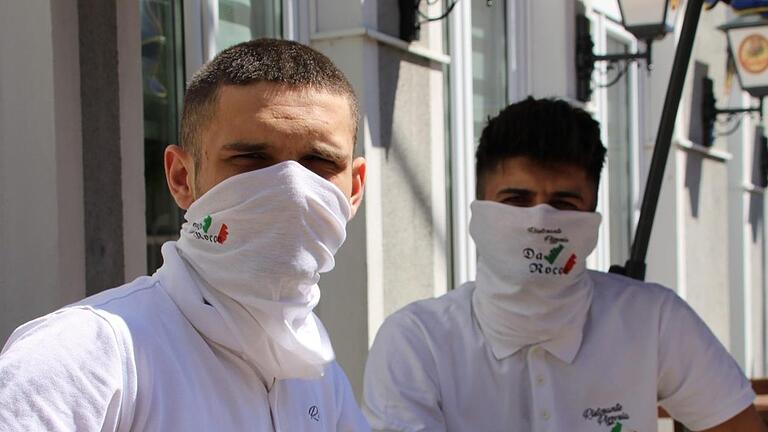 Für viele Geschäftsleute und Gastronome wird die Maske zum ständigen Begleiter. Auf dem Bild tragen Veselj (links) und Alban Mahmudi vom Restaurant Da Rocco den Mund- und Nasenschutz. Foto: Ulrike Müller       -  Für viele Geschäftsleute und Gastronome wird die Maske zum ständigen Begleiter. Auf dem Bild tragen Veselj (links) und Alban Mahmudi vom Restaurant Da Rocco den Mund- und Nasenschutz. Foto: Ulrike Müller