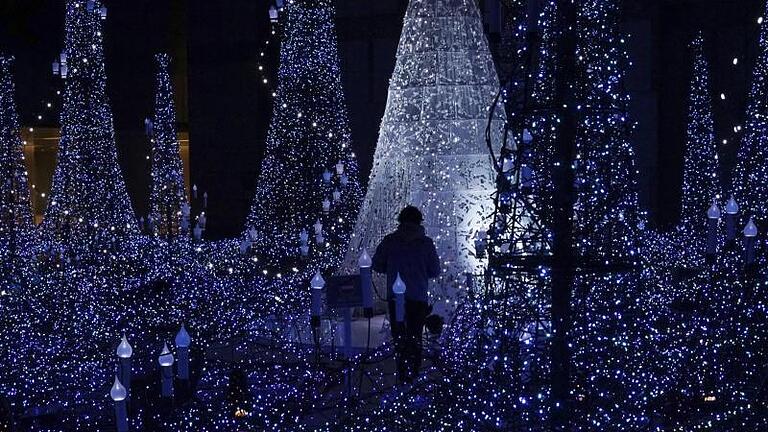 Ein Mann steht inmitten der Weihnachtsbeleuchtung im Tokioter Bezirk Shiodome. Foto: Eugene Hoshiko       -  Ein Mann steht inmitten der Weihnachtsbeleuchtung im Tokioter Bezirk Shiodome.