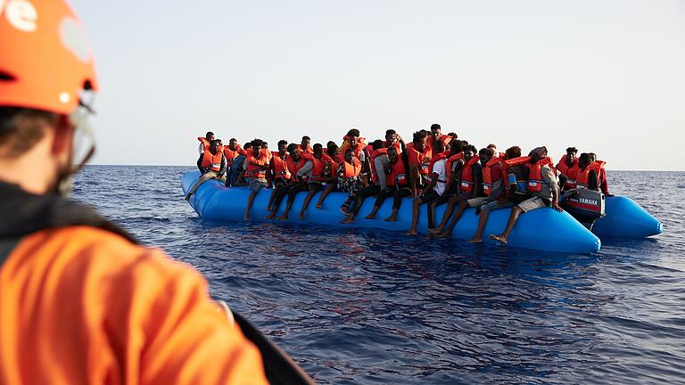 Die von der Seenotrettungsorganisation Sea-Eye herausgegebene Aufnahme zeigt einen Seenotretter,&nbsp; der zu einem Flüchtlingsboot schaut Archivbild.&nbsp;