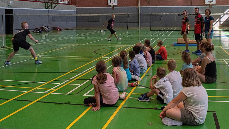 Gebannt beobachten die Kinder die Badminton-Demonstration von Andreas Ortlauf (links) und Leo Ziegler (rechts) beim Ferienprogramm des BC Bad Königshofen. Im Hintergrund verfolgen auch die Sportwartin Conny Helmreich (rechts) sowie die Betreuer Jonas Hummel und Lisa Helmreich das Spiel.