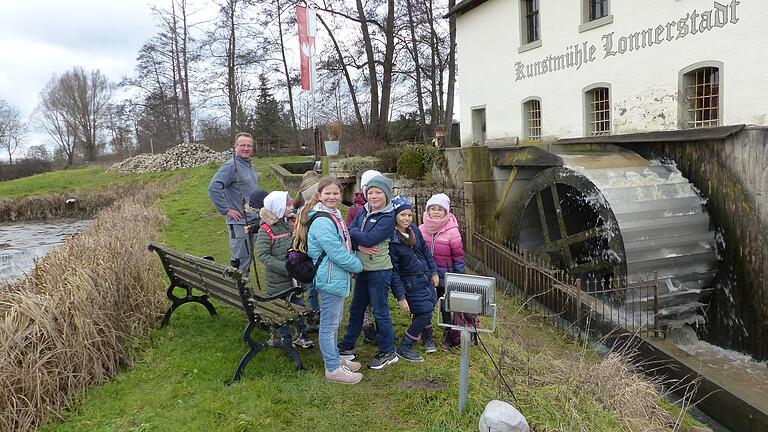 Paul Bruckmann zeigt den Geiselwinder Kommunionkindern das Mühlrad der historischen Kunstmühle Lonnerstadt.