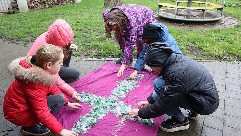 Gemeinsam ordnen die Kinder die Glasscherben, mit denen das Kreuz am Karfreitag gestaltet wird.