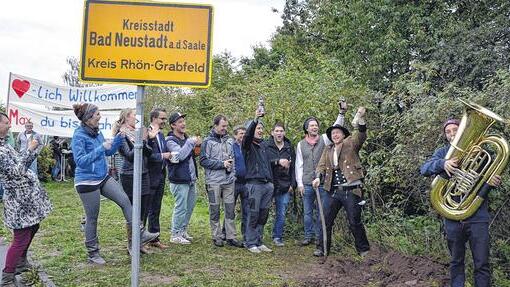 Ausgeliehenes Schild: An der Stelle, an der Maximilian Herde (Zweiter von rechts) vor drei Jahren eine Schnapsflasche vergrub, empfing Bad Neustadt den Walz-Heimkehrer mit großem Hallo.