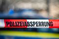 Polizeiabsperrung       -  Ein Absperrband mit der Aufschrift &bdquo;Polizeiabsperrung&rdquo; ist vor einem Polizeiwagen aufgespannt.