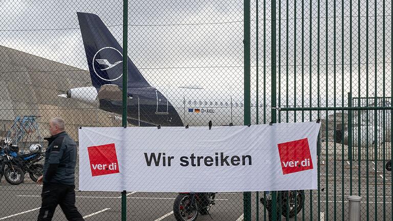 Erneuter Warnstreik des Lufthansa-Bodenpersonals.jpeg       -  „Wir streiken“ steht auf einem Plakat an einem Tor des Flughafens Frankfurt. Die Gewerkschaft Verdi kämpft für höhere Löhne für das Bodenpersonal der Lufthansa. Über Osten drohen weitere Streiks.