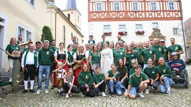 Beste Stimmung zum 'Wochenende des Jahres' – der Dorf-Kirchweih. Alle Beteiligten des Kirchweihumzugs am Sonntagnachmittag, die Kirchweihmädels und -burschen vom Verein Stadelon und die Blaskapelle stellten sich zum Foto auf, selbstverständlich vor ihrem kulturellen Wahrzeichen, der St. Bartholomäuskirche und dem ehemaligen Rathaus.