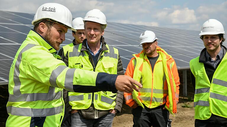 Beim Ortstermin auf der Baustelle erläutert Projektingenieur Benedikt Bausenwein (vorne von links) dem Vorsitzenden der Geschäftsführung von Belectric, Ingo Alphéus, die Vernetzung der Anlage mit dem&nbsp;Umspannwerk zwischen Brünnstadt und Zeilitzheim. Anwesend waren auch Baustellenleiter Sven Friedrich und Projektleiter Steven Gerold.