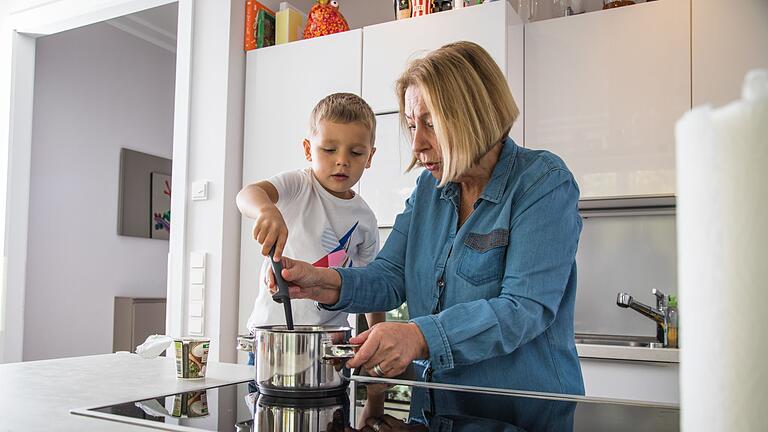 Oma kocht mit Enkel       -  Beim gemeinsamen Kochen ist Vorsicht geboten: Heiße Töpfe und spritzende Flüssigkeiten können schnell zu Verbrühungen führen.