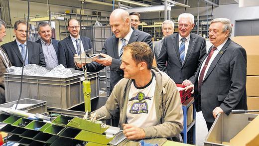 Passende Verbindung: In der Fertigung bei Kindermann werden unter anderem Anschlusskomponenten für die Konferenztechnik montiert. Gemeinsam mit Vertretern von Landratsamt und Verbänden besuchte Landrat Eberhard Nuß (Mitte) das Eibelstadter Unternehmen; rechts im Bild Bürgermeister Heinz Koch und Firmenchef Paulinus Hohmann.