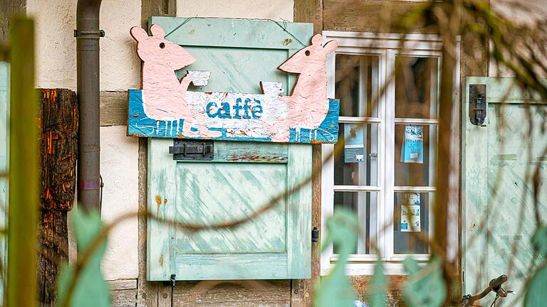 Ein Holzschild mit Mäusen weist auf das 'Café im Kunsthandwerkerhof' hin, das allerdings schon seit längerer Zeit geschlossen ist.