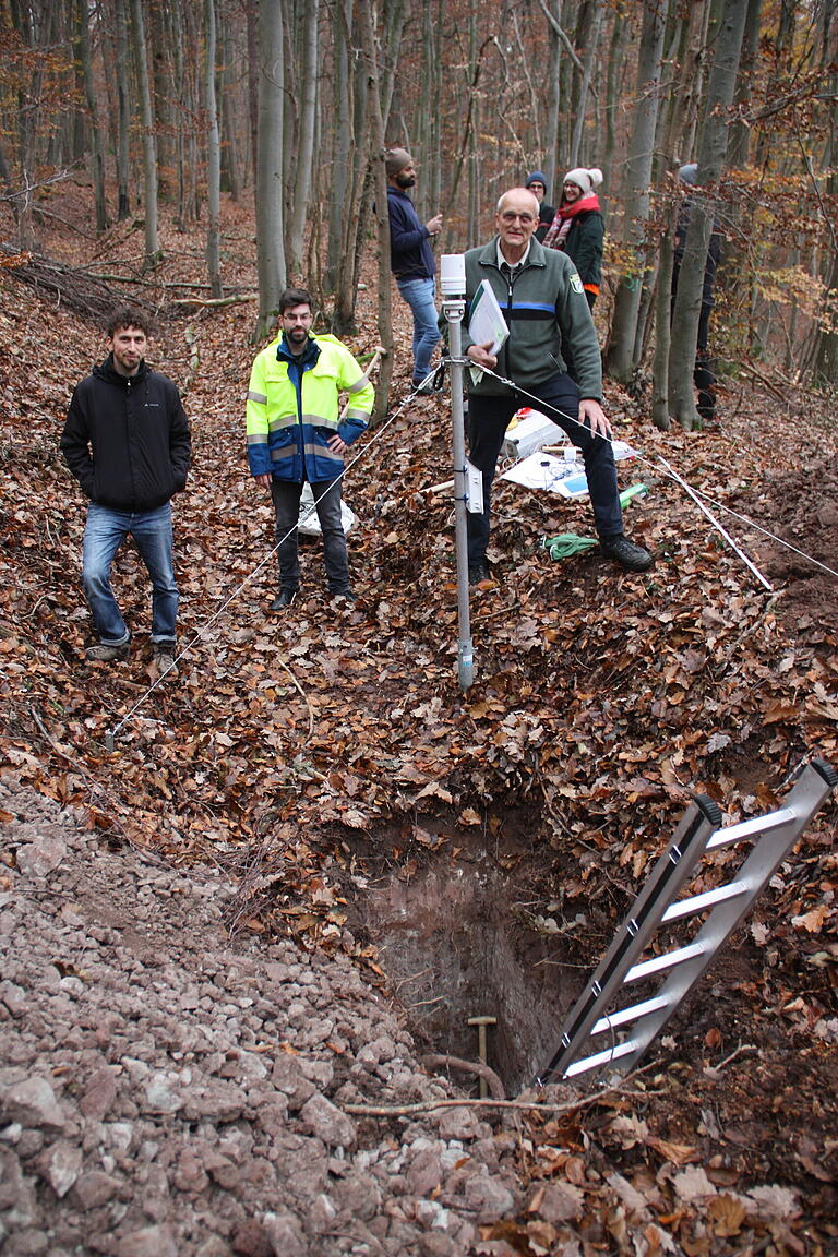 Rund zwei Meter tief ist das Loch, das die Wissenschaftler in einer vorhandenen Furche im Wald gegraben haben. Darüber werden die Messsonden in den Waldboden eingebracht. Das Bild zeigt (vorne von links) den Versuchsleiter Lucas Alcamo von der TU München, Benjamin Schulz, den Fachbereichsleiter Wasserversorgung, Grundwasser und Bodenschutz vom Wasserwirtschaftsamt Bad Kissingen, und Andreas Leyrer, den Forstlichen Leiter des Steigerwald-Zentrums.