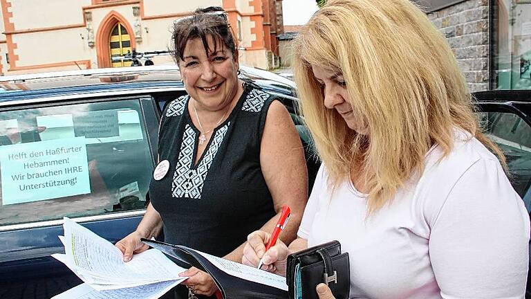 Christa Henning aus Hofheim (rechts) unterschreibt auf einer Unterschriftenliste, mit der Hebamme Carola Lutsch (links) und deren Kolleginnen sich gegen die Schließung der Haßfurter Geburtshilfe wenden.