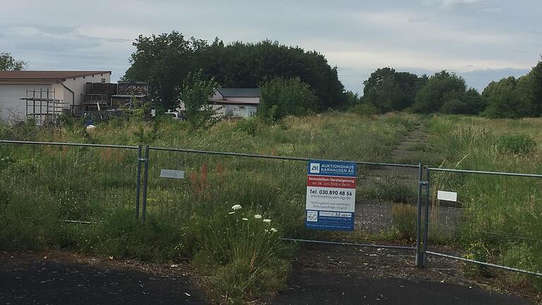 Mit einem Plakat am Zaun hat das Auktionshaus Karhausen am recht verwilderten ehemaligen Bahngelände in Alitzheim für die Versteigerung geworben. Mit einem Plakat am Zaun hat das Auktionshaus Karhausen am recht verwilderten ehemaligen Bahngelände in Alitzheim für die Versteigerung geworben.
