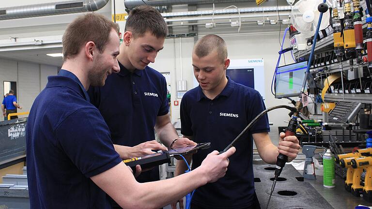 Die Auszubildenden Jan Eyring (links), Noah Schultheis (Mitte) und Willi Reininger (rechts) führen bei einer Druckluftpistole eine Leckage-Messung durch. Gibt es Druckluftverluste, kostet das Siemens viel Geld.