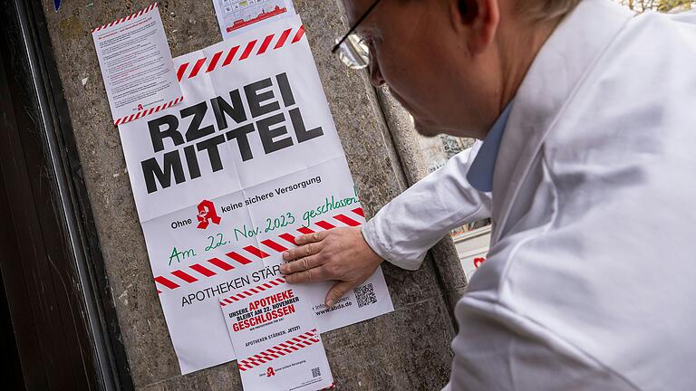 Ein Apotheker befestigt ein Plakat zum Apotheker-Streik am Mittwoch, 22. November (Symbolbild). Auch ein Großteil der Apotheken in Rhön-Grabfeld bleibt am Protesttag geschlossen.&nbsp;