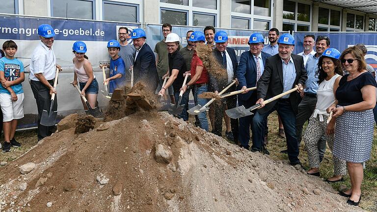 Nicht nur die Schülerinnen und Schüler und der Direktor der Rupert-Egenberger-Schule spielen gerne mit Sand, auch für Poltikerinnen und Politiker, für Architekt und Bauleiter und für den Schulleiter ist der Sandhaufen beim Spatenstich ein Vergnügen.