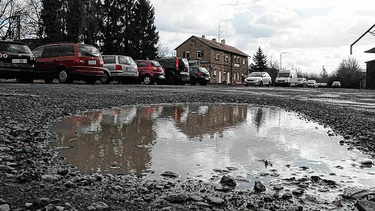 Schotter für den Parkplatz       -  Immer wieder aufs Neue ist es für die Frau ein Ärgernis, wenn sie auf dem Parkplatz in der Hofheimer Bahnhofstraße, zwischen den Bahngleisen und dem Lagerhaus, ihr Auto abstellt, denn dann beginnt das &bdquo;Wassertreten&ldquo;. Sie ärgert sich: &bdquo;Sollen wir extra Schuhwerk fürs Laufen über den Parkplatz anziehen?&ldquo;, fragt die Verkäuferin. Besonders nach den Regenfällen der vergangenen Tage ist der öffentliche Parkplatz auf dem geschotterten Gelände wieder übersät mit Schlaglöchern voller Wasser.   Eine Hofheimerin, die dort gerade ihr Fahrzeug abgestellt hat, nimmt's einigermaßen mit Humor: &bdquo;Das ist der Parkplatz 'Seen-Land'.&ldquo; Und fügt hinzu: &bdquo;Als es die ganze Zeit gefroren hatte, da ging's ja noch&ldquo;. Aber nachdem es nun getaut und geregnet hat, macht der Parkplatz dem Namen &bdquo;Seen-Land&ldquo; alle Ehre (wenngleich die Perspektive des Bildes ein wenig übertreibt). Abhilfe soll kommen, erklärt auf Anfrage der Redaktion, Hofheims Bürgermeister Wolfgang Borst. Die Löcher werden mit Schotter aufgefüllt. Allerdings hätten die Mitarbeiter des Bauhofs derzeit alle Hände voll mit den vielen Rohrbrüchen im Stadtgebiet zu tun. Foto: Alois Wohlfahrt