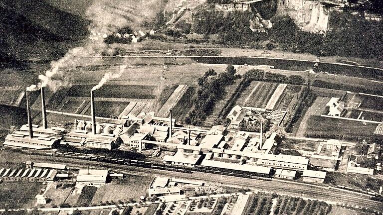 Nachbarn: Das Luftbild von 1920 zeigt in der Mitte die Portland-Zementfabrik, darüber jenseits des Mains den Steinbruch mit den Häusern von Kleinlaudenbach. Unten liegt das Eisenwerk Laufach (Düker) im Winkel zwischen Bahngleisen und einem Weg, der heute die Würzburger Straße, Bundesstraße 27, ist.