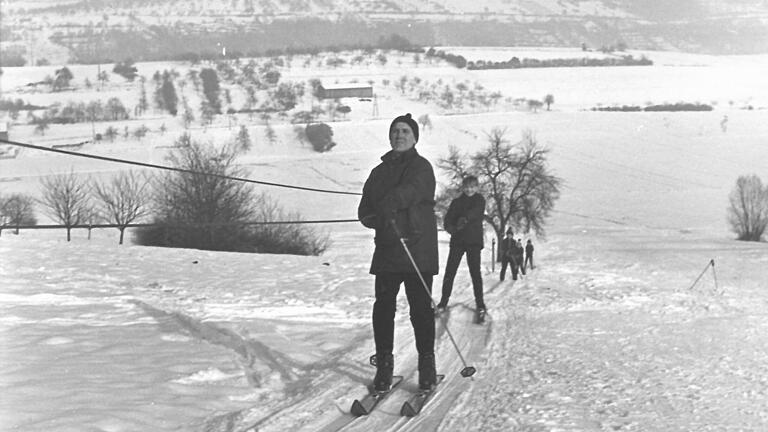 1965: Eine lange Reihe von Skifahrern zieht der improvisierte erste Dirmbachlift den Hang hinauf.