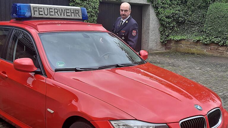 Der scheidende Kreisbrandrat Roland Eckert neben seinem Dienstauto mit dem passenden Kennzeichen KT-RE 112.