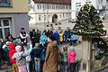 Vorschulkinder des AWO Kindergartens mit Bürgermeister Alexander Knahn sowie Vorsitzende Magdalena Roßbach und Helferinnen am geschmückten Brunnen am Höchberger Marktplatz.
