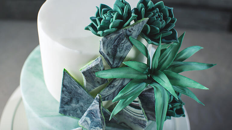 Wedding cake decorated like a stone marble with green flowers       -  Artwork. Bunk Wedding cake decorated like a stone marble with green flowers and leaves of agave on a background of fabric. food design. trends