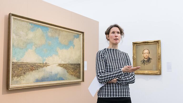 Henrike Holsing, stellvertretende Direktorin des Museums im Kulturspeicher, neben zwei Werken, die in der NS-Zeit von Wolfgang Gurlitt erworben wurden: 'Schottisches Hochmoor' von Karl Heffner (links) und 'Bildnis eines bärtigen Mannes von Max Slevogt (rechts).