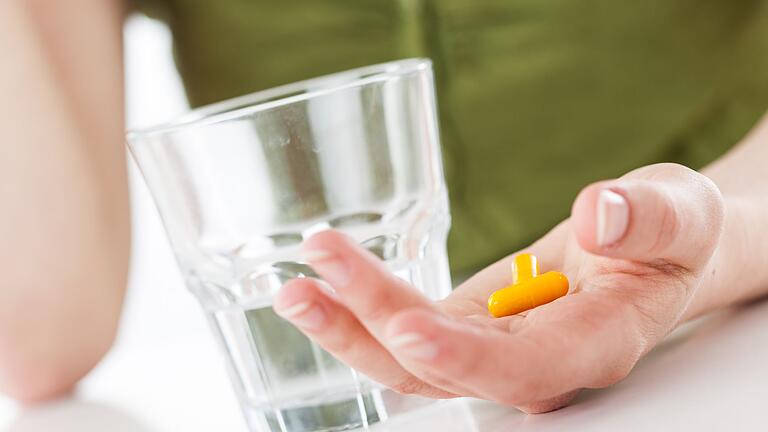 Eine Person mit Tablette und Wasserglas - Nahrungsergänzungsmittel mit Vitamin B12 sind vor allem bei einer veganen oder vegetarischen Ernährung wichtig. Eine Person mit Tablette und Wasserglas - Nahrungsergänzungsmittel mit Vitamin B12 sind vor allem bei einer veganen oder vegetarischen Ernährung wichtig.