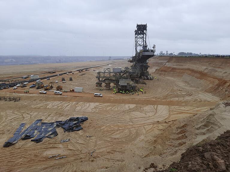 Wie groß das Abbaugebiet und die Maschinerie vor Ort ist, verdeutlichen die gelb gekleideten RWE-Mitarbeiter neben dem Kohlebagger. Auf der rechten Seite ist die Abbruchkante zu sehen.