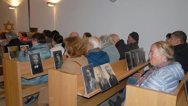 Die Teilnehmer an der Gedenkfeier nahmen Bilder deportierter Juden mit zu ihren Plätzen in der Alten Synagoge.