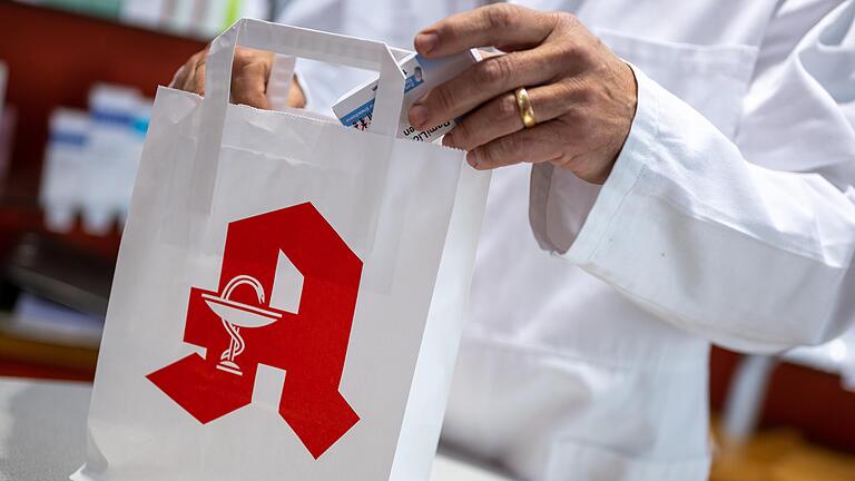 Patienten sollten sich rechtzeitig mit Medikamenten eindecken. Am 14. Juni schließen landesweit fast alle Apotheken. Das Symbolbild zeigt einen Apotheker, der eine Packung Tabletten in eine Tüte steckt.