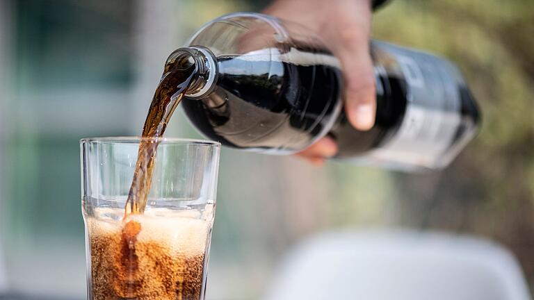 Ein Mann schenkt Cola ein - Trinken wir Getränke mit Kohlensäure, gelangt Luft in den Magen. Und die muss wieder heraus. Ein Mann schenkt Cola ein - Trinken wir Getränke mit Kohlensäure, gelangt Luft in den Magen. Und die muss wieder heraus.