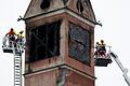 Nach Brand in Seniorenheim in München       -  Feuerwehrleute sichern mit Spanngurten lose teile an dem beschädigten Turm des Seniorenheimes.
