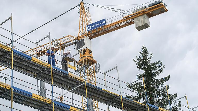 Der Polier (rechts) wirft beim Richtfest für die neue Modellfabrik des SKZ im Gewerbegebiet Ost in Würzburg ein Weinglas vom Dach.