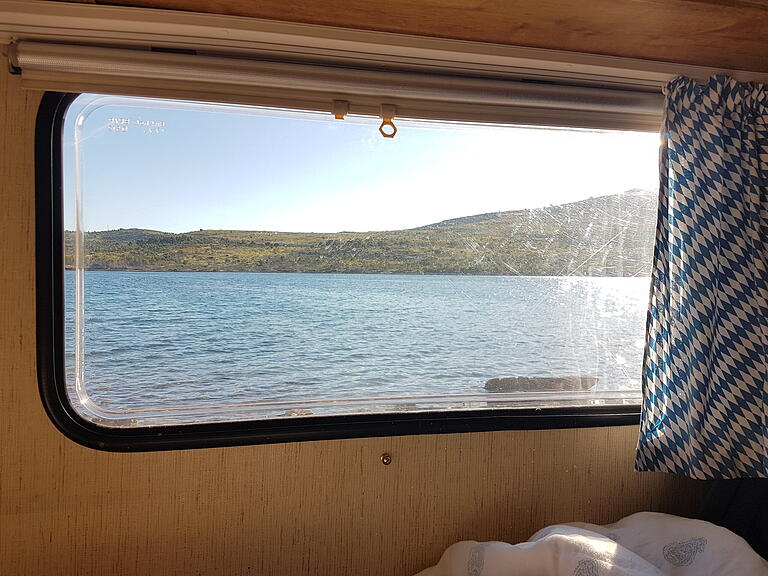 Morgendlicher Blick aus dem Wohnwagen-Inneren auf Meer und Küstenlandschaft bei Zadar an der kroatischen Adria. Morgendlicher Blick aus dem Wohnwagen-Inneren auf Meer und Küstenlandschaft bei Zadar an der kroatischen Adria.
