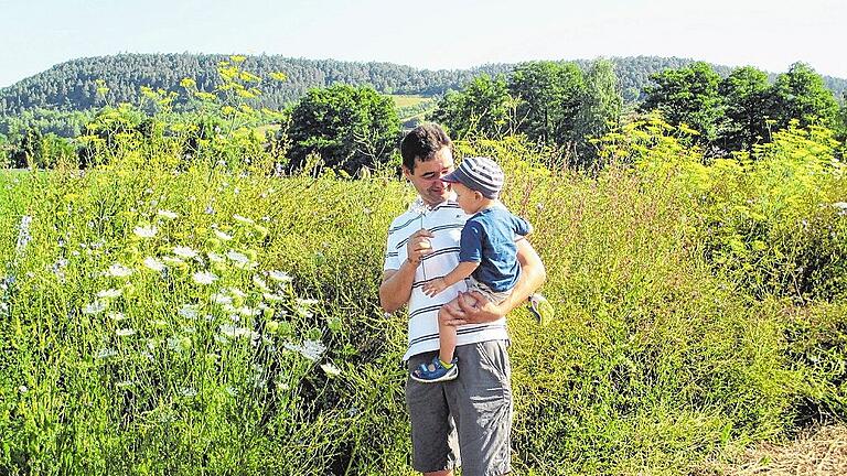 Landwirt Jochen Then aus Burglauer zeigt seinem jüngsten Sproß begeistert die Vielfalt der Pflanzen in den angelegten Gewässerschutzstreifen.