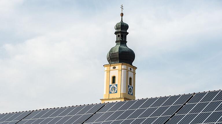 Solaranlage vor Kirchturm       -  So sollte es nach dem Plan der Staatsregierung bis 2025 auf allen geeigneten staatlichen Dächern aussehen: Solarmodule produzieren klimafreundlichen Strom. (Archivbild)