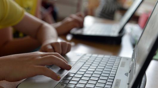Kinder am Computer       -  Eine Schülerin tippt auf der Tastatur ihres Laptops.