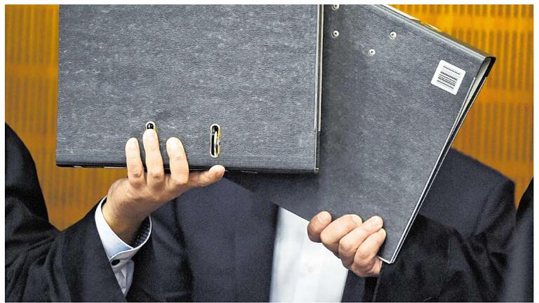 Zwei Aktenordner auf halber Zeitungsseite       -  Ein Foto das zeigt, wie das Gesicht eines Angeklagten von seinen Anwälten verborgen wird. Aber eine halbe Zeitungsseite muss man damit nicht belegen.