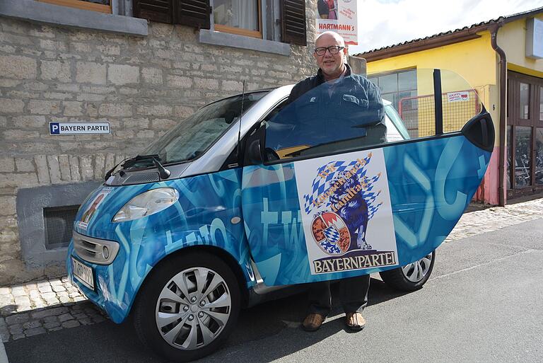 Ein Bild aus besseren Tagen: Uwe Hartmann vor seinem Haus in Kitzingen mit seinem Bayerpartei-Smart.