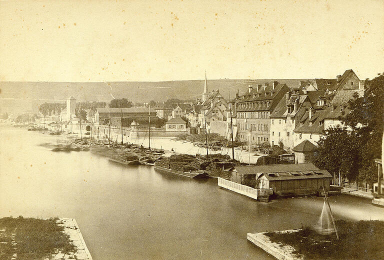 Holzplatz und Kranenbastion von der Alten Mainbrücke aus. Das Bild von 1885 zeigt im Vordergrund rechts das Wellenbad, eines der im Main festgemachten Würzburger Schwimmbäder. Dahinter liegen mit Holz beladene Schiffe; in der nahegelegenen Kärrnergasse wohnten die Kärrner, die Fuhrleute, die das Holz mit ihren Karren weitertransportierten. Holzplatz und Kranenbastion von der Alten Mainbrücke aus. Das Bild von 1885 zeigt im Vordergrund rechts das Wellenbad, eines der im Main festgemachten Würzburger Schwimmbäder. Dahinter liegen mit Holz beladene Schiffe; in der nahegelegenen Kärrnergasse wohnten die Kärrner, die Fuhrleute, die das Holz mit ihren Karren weitertransportierten.
