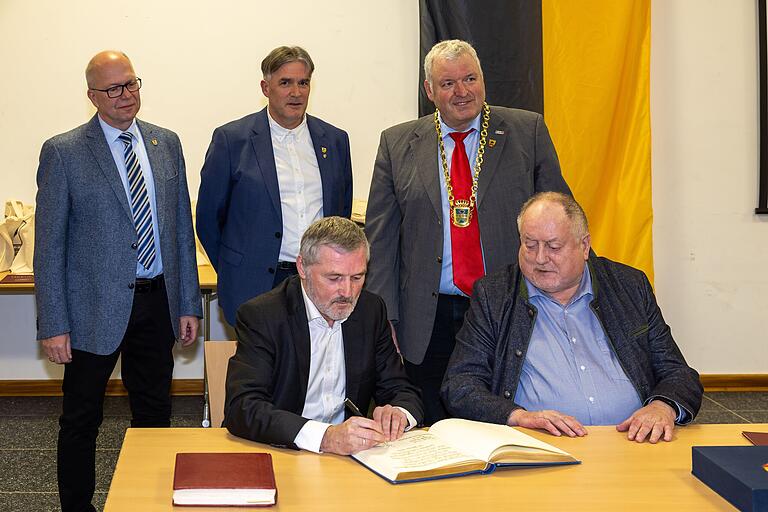 Bürgermeister Jürgen Hennemann (mit Amtskette) und seine Stellvertreter Harald Pascher (hinten Mitte) und Thomas Limpert (hinten links) beobachten die beiden Pfarrer im Ruhestand Bernd Grosser (links) und Pater Rudolf Theiler beim Eintrag in das Goldene Buch der Stadt. Bürgermeister Jürgen Hennemann (mit Amtskette) und seine Stellvertreter Harald Pascher (hinten Mitte) und Thomas Limpert (hinten links) beobachten die beiden Pfarrer im Ruhestand Bernd Grosser (links) und Pater Rudolf Theiler beim Eintrag in das Goldene Buch der Stadt.